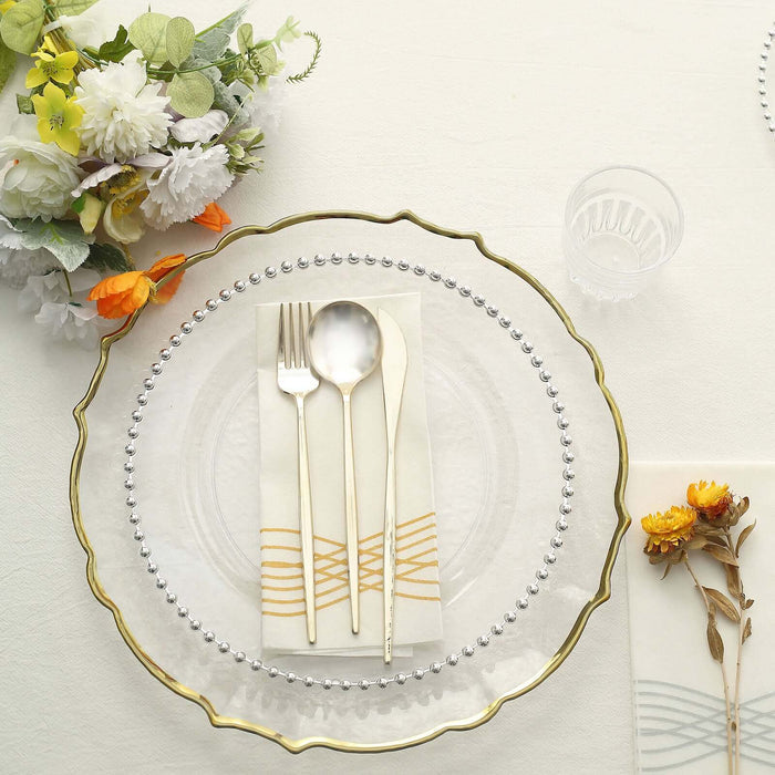 Elegant gold-accented plate setting with cutlery and floral centerpiece.