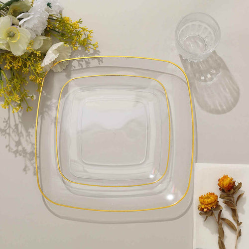 Set of three clear glass plates with gold rim on a neutral background.