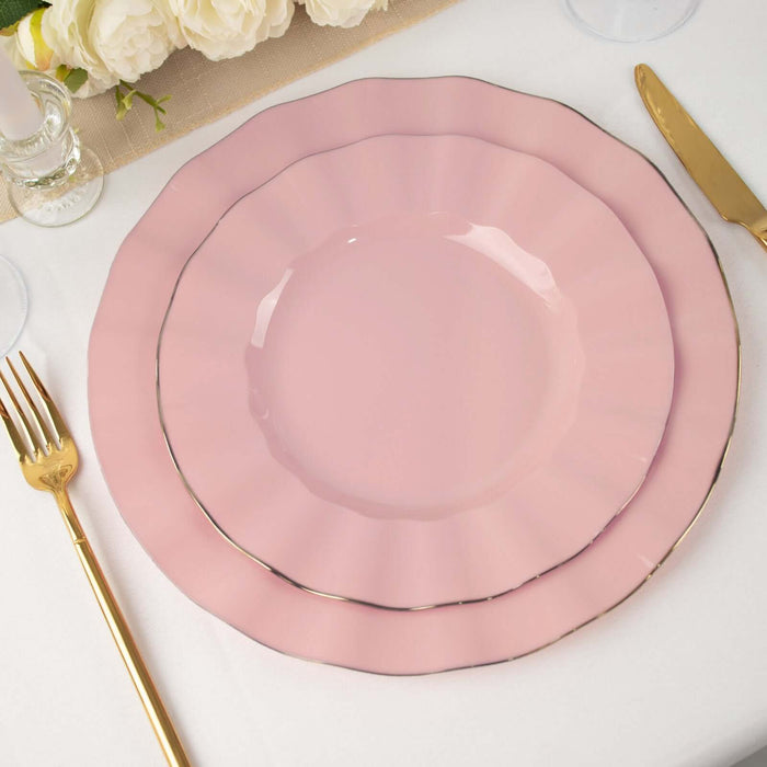 Pink ruffled plates set on a table with gold cutlery and floral decor.