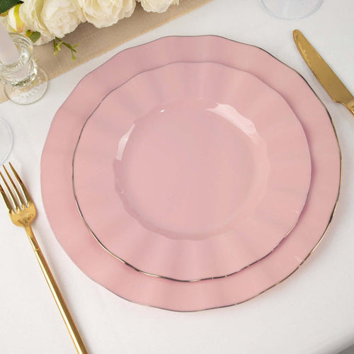 Pink ruffled plates set on a table with gold cutlery and floral decor.