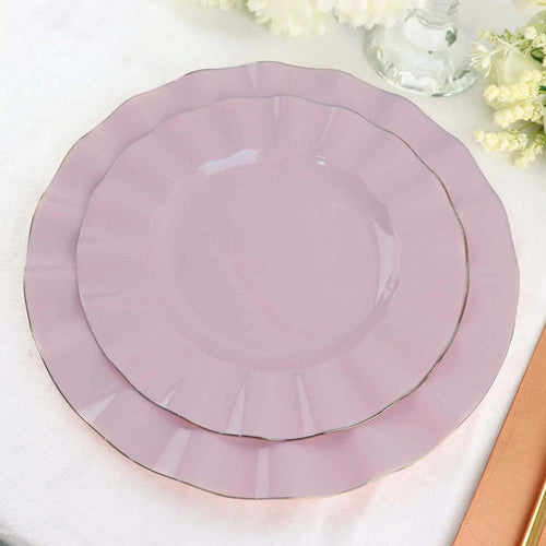 Pink scalloped plates with gold trim, stacked on a white tablecloth.