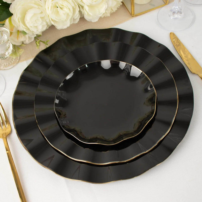 Elegant black plates with gold trim stacked on a table setting.