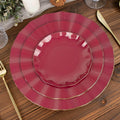 Elegant maroon and gold dinner plates stacked on a wooden table.