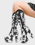 THE WILD ICON
  
  Cowgirl Platform Knee High Boots in Cow Print faux suede. These vegan Platform Boots feature an ICONIC western cow print and High Platform sole and heel, the only choice for festival goers. Made with eco-friendly materials and 100% cruelty-free, these boots are as ethical as they are wild!
  
  
  - Platform Height: 2.5 inch
  - Heel Height: 5.5 inch 
  - Knee High length
  - Black zipper 
  - Western neck
  - Platform sole
  - Pointed toe 
  - 100% vegan 
  
  SKU: LMF 376 - White Cow