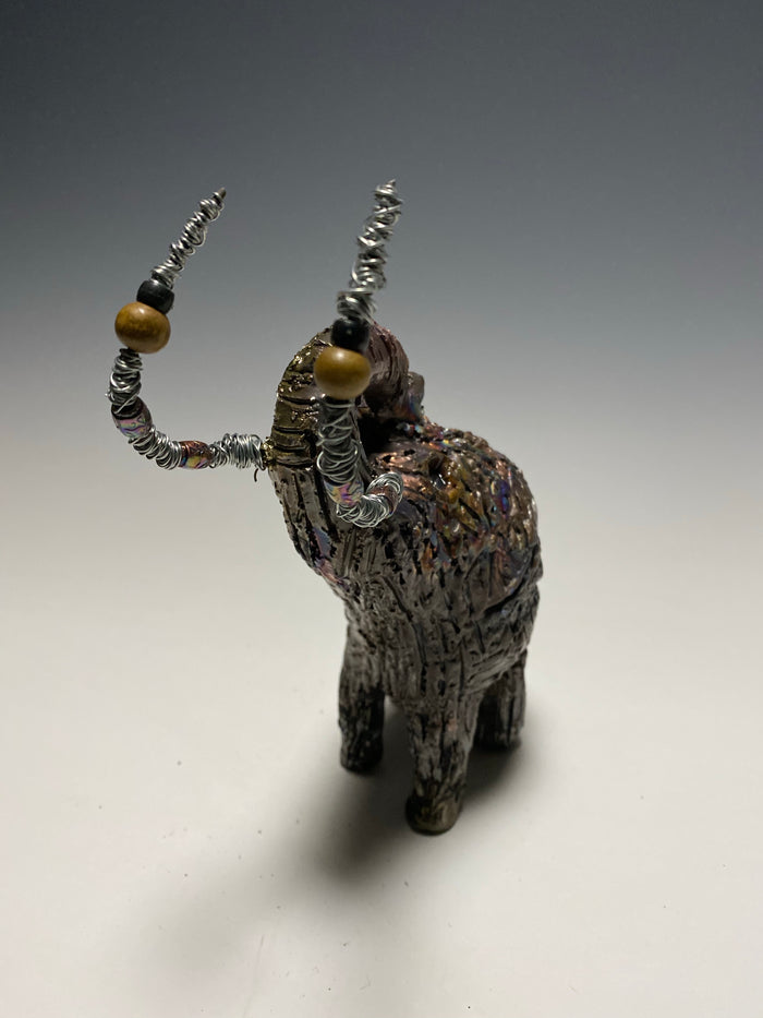 Raku Elephant Have you HERD!!!!!!  Just one of these lovely Raku Fired Elephant will make an excellent gift for your  friend, sorority or for your home’ special place centerpiece.  6" x 4" x 4" 1lbs Wood beaded with  silver tusk Beautiful metallic raku colors For decorative purposely only.