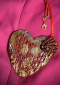 Have A Heart ! Each heart pendant is handmade with love! It is 3"x 3" and weighs approx. 3ozs. This pendant has a red violet and gold metallic raku glazes that renders a unique translucent  patina. The heart has a textured pattern . Both sides are  are different and equally beautiful! It holds a spiral of red violet mini beads on a spiral copper wire. This pendant has a nice 12" red suede cord!