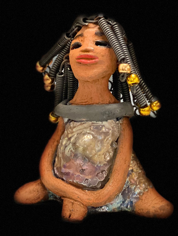 Meet Sadie  Sadie stands 5.5" x 4" x 3" and weighs 8.7 ozs. She wears a lovely glossy  metallic gold dress.. Sadie has over15 feet of coiled wire hair. Sadie appears to sit in a yoga pose. Her long arms rest at her side. Sadie is a great starter piece from the Herdew Collection!