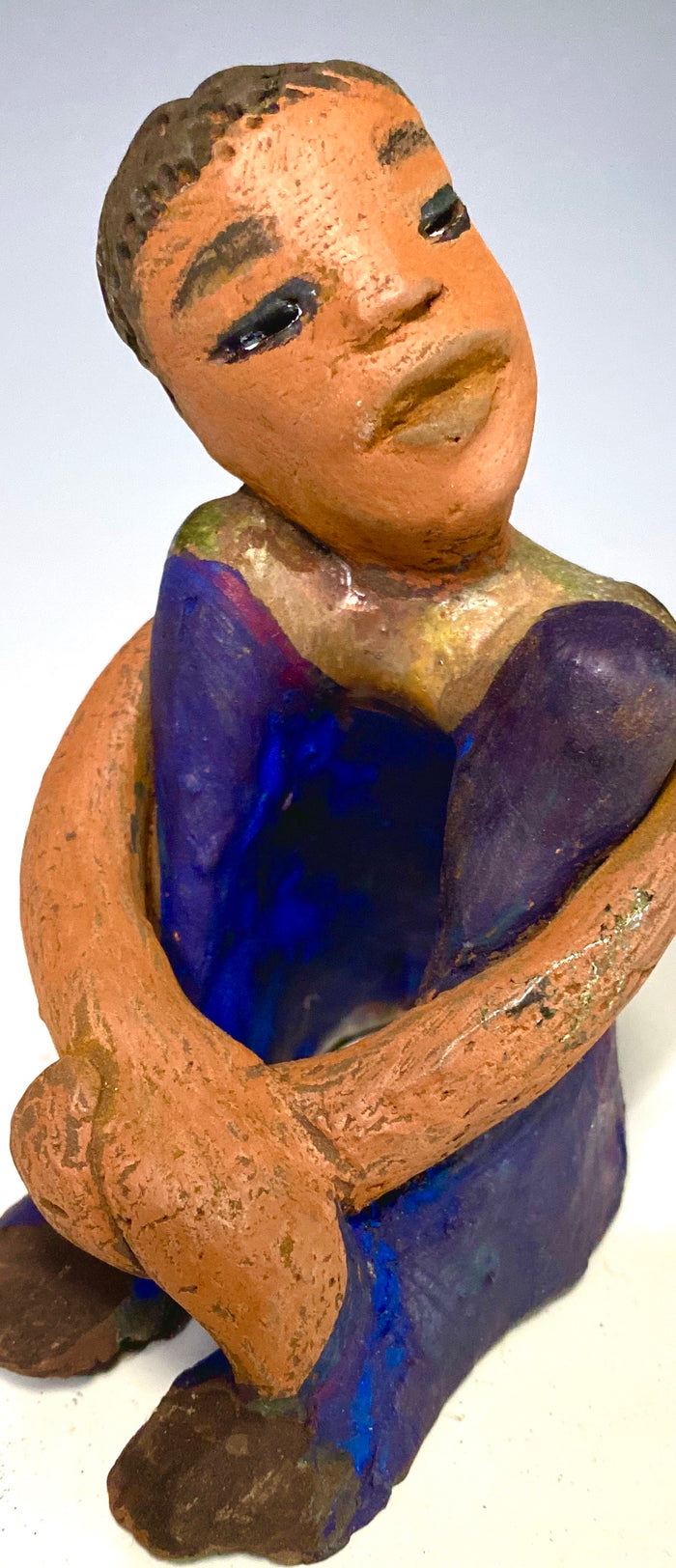 Paul is a Handsome Mischief Guy!  Do you see the wit in his face?  Paul stands 4.5"x 3" x 3" and weighs 6.9 ozs. He has a shimmery metallic tee shirt. Paul's complexion is honey brown. His arms are folded around his legs as he ponders another mischief moment!