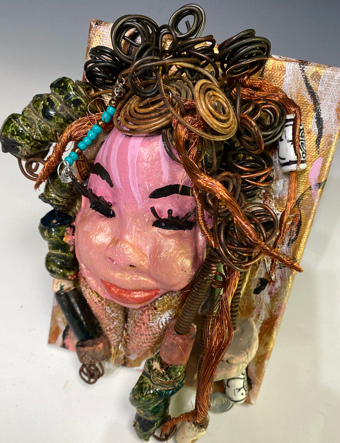 Peggy has a pink and white complexion with ruby red lips! She is mounted on a  5” x 7” and weighs 1.2 lbs. Peggy  has an awesome blue tribal beaded hair dress. She has over 30 feet of coiled 16 gauge wire and copper strands of hair.