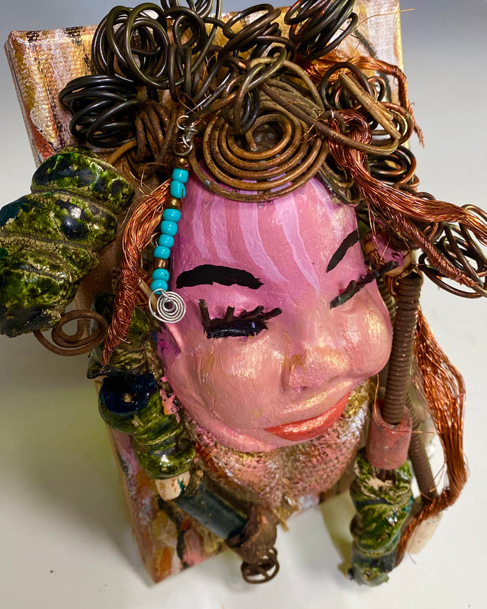 Peggy has a pink and white complexion with ruby red lips! She is mounted on a  5” x 7” and weighs 1.2 lbs. Peggy  has an awesome blue tribal beaded hair dress. She has over 30 feet of coiled 16 gauge wire and copper strands of hair.