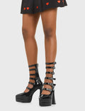 READY TO WEAR
  
  Revolution Platform Ankle Boots in Black patent. These platform boots feature six adjustable straps with silver buckles and eyelets. Made with eco-friendly materials and 100% cruelty-free, these platform boots are as ethical as they are chic.
  
  - Platform Height
  - Six adjustable strap
  - Silver buckles and eyelets
  - Flared heel
  - Pointed toe
  - High Heel
  - 100% vegan 
  
  SKU: LMF 3529 - BlackPAT