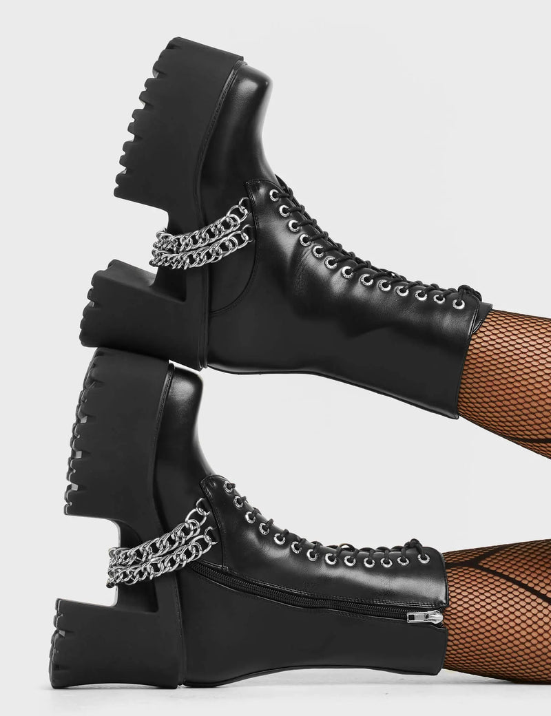 FAST LANE Step On It Chunky Platform Ankle Boots in black faux leather. These black vegan Platform Boots feature lace up design with sillver eyelets and two silver aestehtic chains. Also includes a functional zip on our rubber grip, chunky platform sole. Made with eco-friendly materials these platform boots are as ethical as they are perfect! - Platform Height: - Black Zipper - Lace Up Design - Silver Eyelets - Silver Chains - Chunky Platform Sole - 100% vegan SKU: LMF 4118 - BlackPU