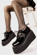 Sweetheart Steps
  
  Stick To It Chunky Platform Creeper Shoes in Black Patent faux leather. These black creeper shoes feature an adjustable black lace up detail with silver eyelets and a adjustable black strap across the upper with heart shaped buckle, leaving a trail of love with every step.
  
  - Platform Height
  - Black Laces with black eyelets
  - Black strap
  - Heart shaped buckle
  - Chunky creeper wedge sole
  - Round Toe 
  - 100% vegan