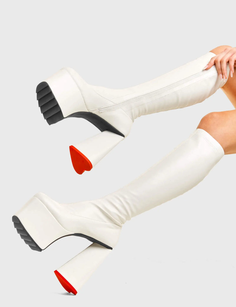 PEACE AND LOVE
  
  Wild Child Platform Knee High Boots in White Fitted Faux Leather. These vegan western Boots feature heart shaped heel, with a red sole and shark teeth grips, very classy. Made with eco-friendly materials and 100% cruelty-free, these boots are as ethical as they are edgy!
  
  
  - Chunky Platform heels
  - Knee length
  - Shark teeth grip
  - Fitted feel
  - Heart shaped heel
  - Red heel sole
  - Rounded toe 
  - 100% vegan 
  
  SKU: LMF 3633 - BlackStretchPU